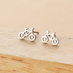 Silver bicycle-shaped stud earrings on a wooden surface
